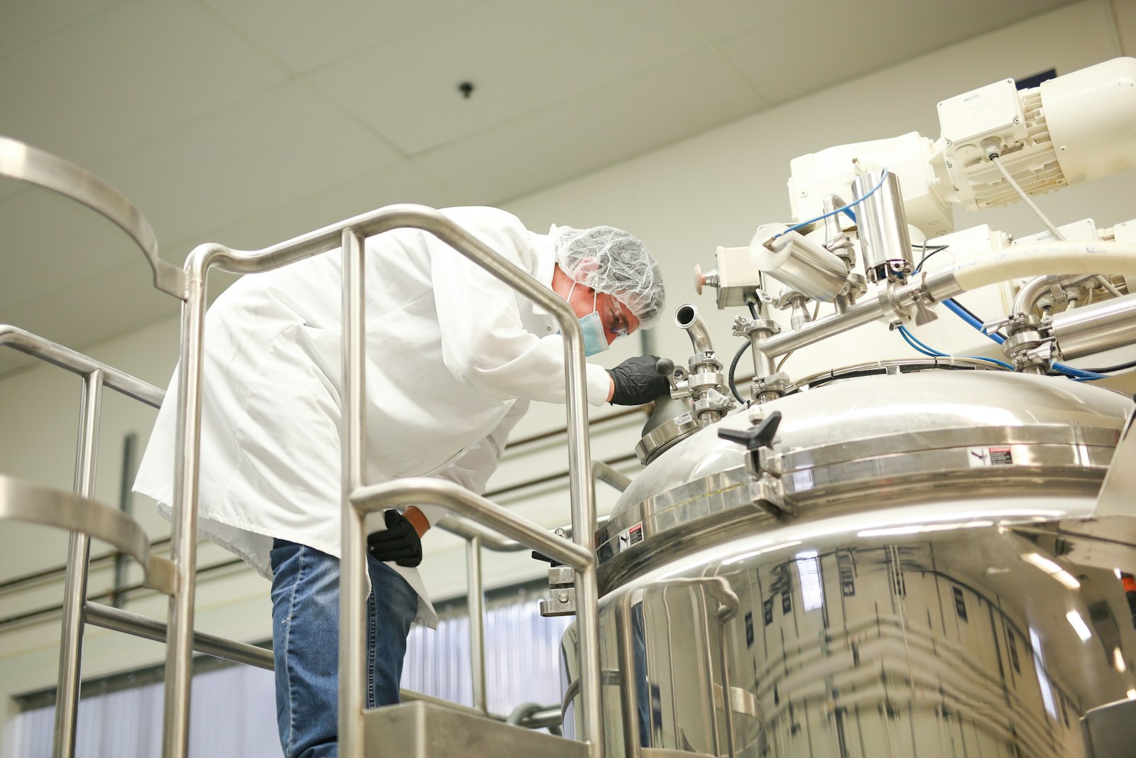 Technician operating a stainless-steel production kettle